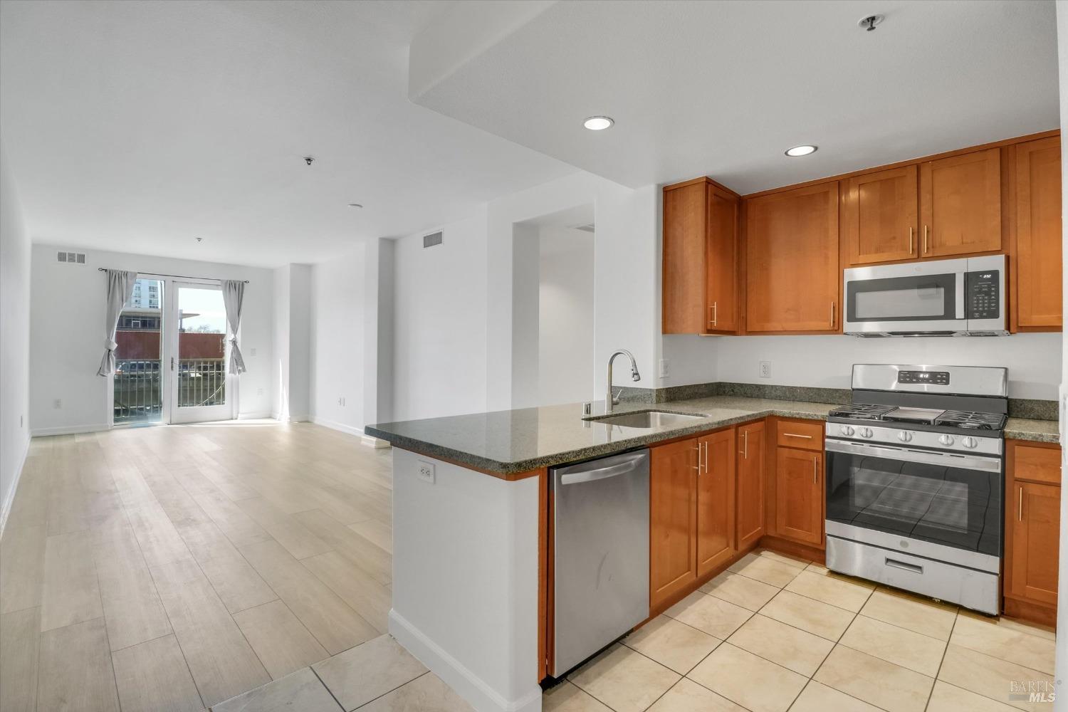 423 7th Street, Unit 105 Oakland, CA 94607 - Photo 6 of 28 a kitchen with stainless steel appliances granite countertop a stove a sink and a microwave