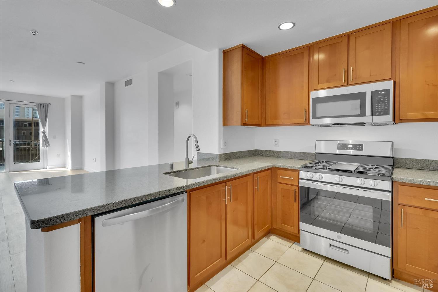 423 7th Street, Unit 105 Oakland, CA 94607 - Photo 8 of 28 a kitchen with stainless steel appliances granite countertop a sink stove and microwave