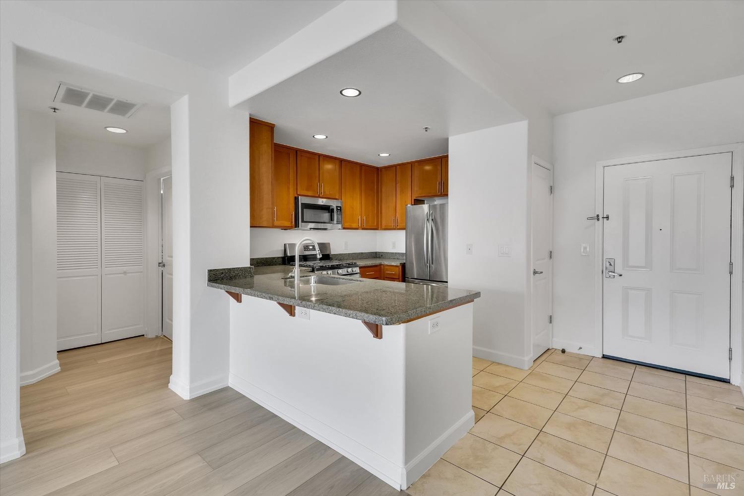 423 7th Street, Unit 105 Oakland, CA 94607 - Photo 10 of 28 a kitchen with stainless steel appliances granite countertop a sink and a stove top oven