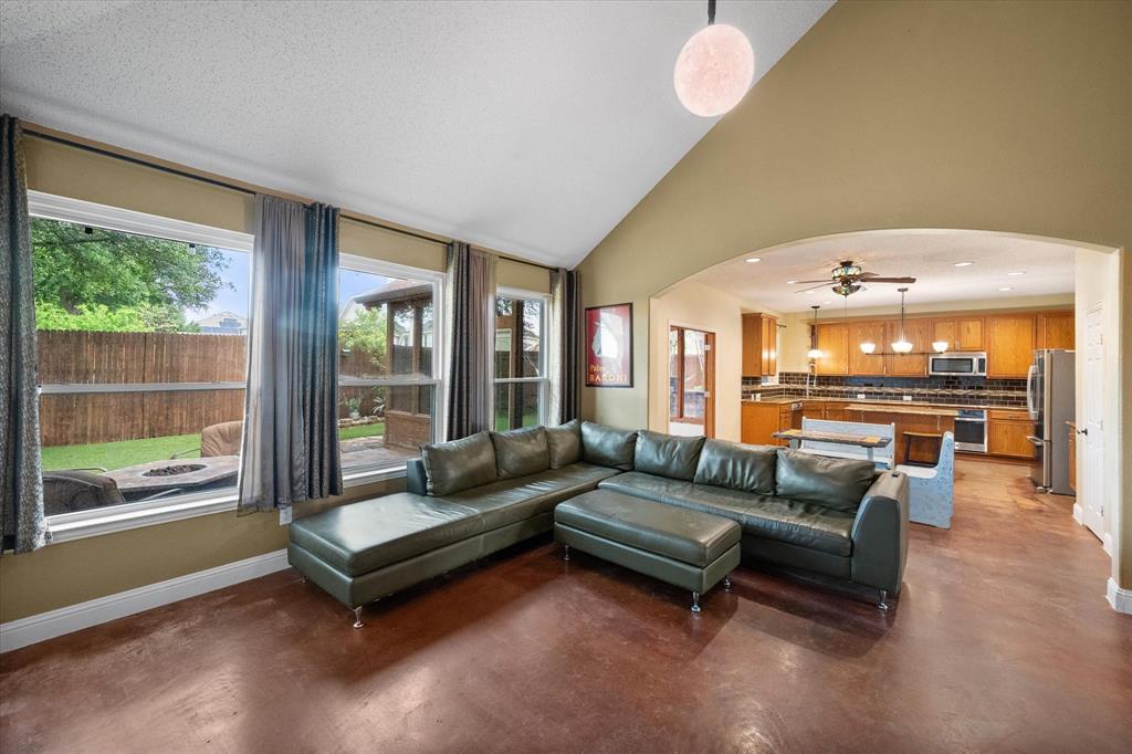 1305 Liverpool Lane Mansfield, TX 76063 - Photo 10 of 40 The living area features vaulted ceilings, large windows providing natural light and views of the yard, and an arched entryway leading to the kitchen