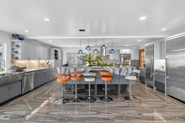 a kitchen with stainless steel appliances kitchen island granite countertop a table chairs sink and cabinets