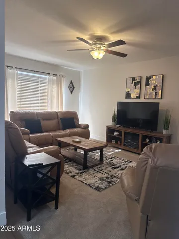 a living room with furniture a flat screen tv and a window