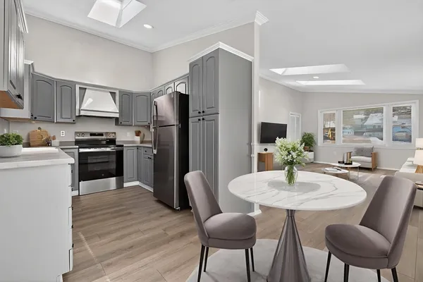 a kitchen with stainless steel appliances granite countertop a refrigerator a stove a sink dishwasher a dining table and chairs with wooden floor