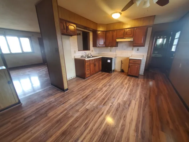 a kitchen with stainless steel appliances a refrigerator a sink dishwasher a stove and white countertops with wooden floor