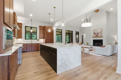 a kitchen with stainless steel appliances kitchen island granite countertop a table chairs and a refrigerator