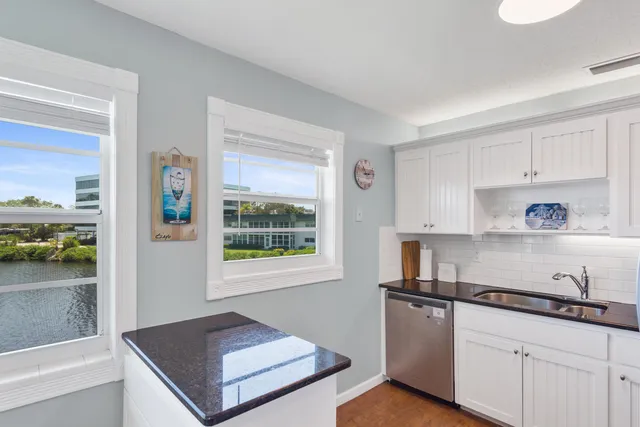 a kitchen with stainless steel appliances granite countertop a refrigerator a sink and white cabinets
