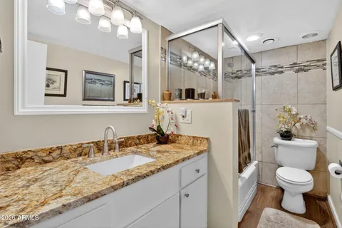 a bathroom with a granite countertop sink mirror vanity and toilet