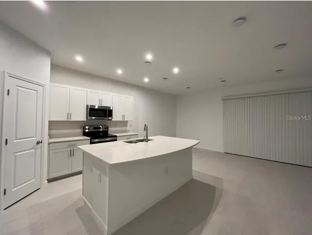 a kitchen with kitchen island a sink stainless steel appliances and white cabinets