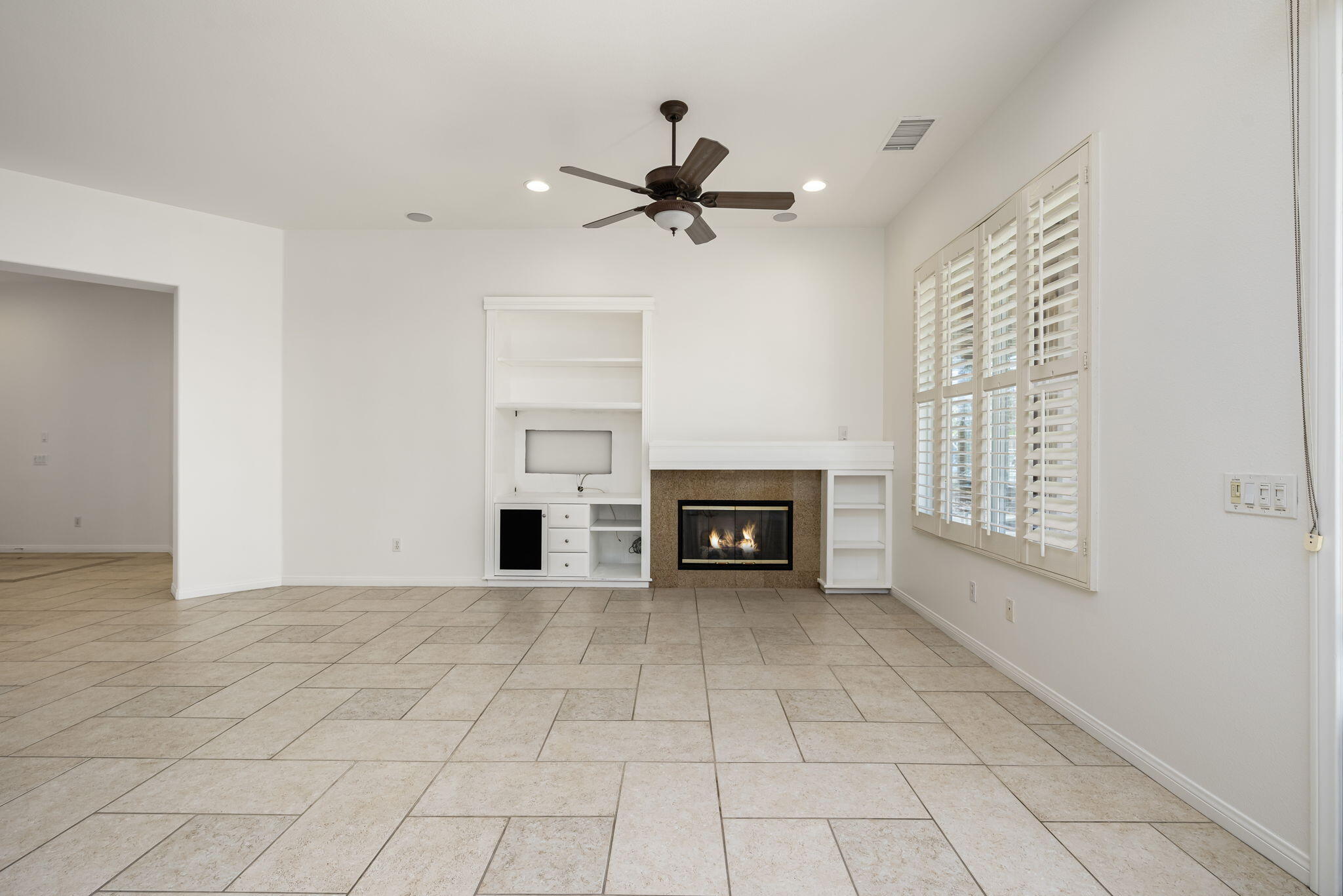 44528 Knightswood Road Indio, CA 92201 - Photo 11 of 46 a view of a livingroom with a ceiling fan windows and a fireplace