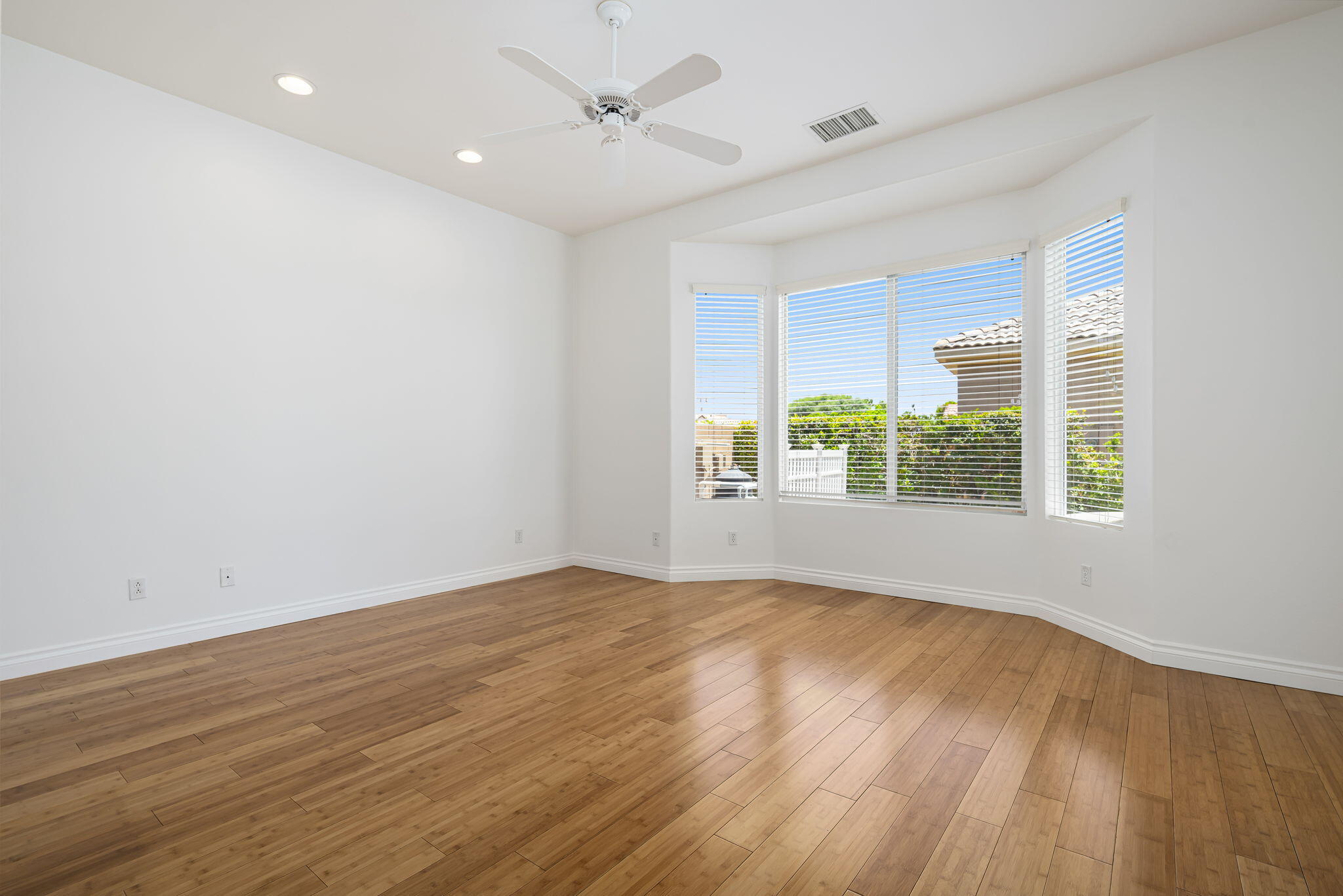 44528 Knightswood Road Indio, CA 92201 - Photo 23 of 46 an empty room with wooden floor and windows