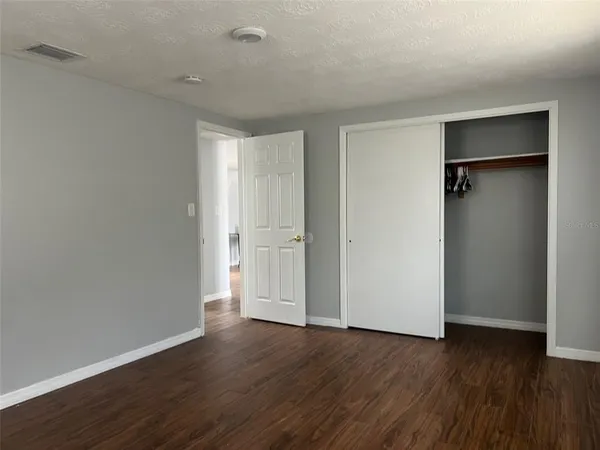 a view of an empty room with wooden floor and closet