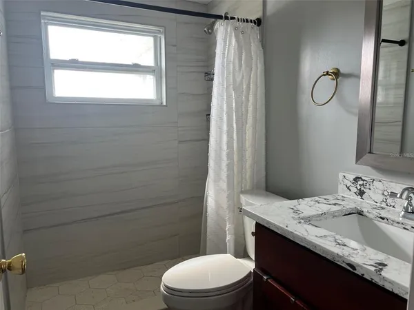 a bathroom with a granite countertop sink toilet and shower