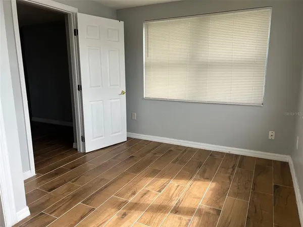 a view of an empty room with wooden floor and a window
