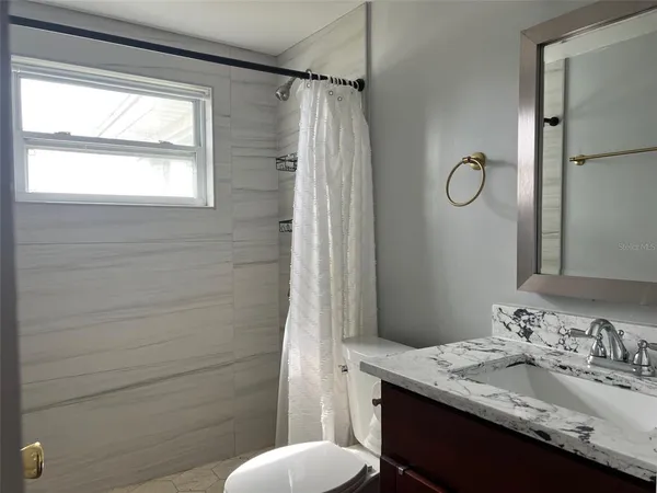 a bathroom with a granite countertop sink toilet and shower