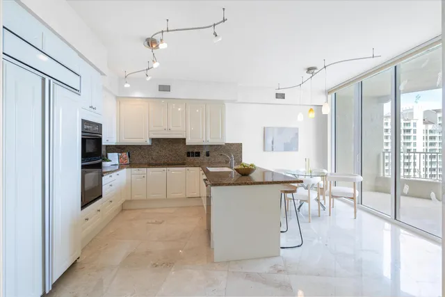 a living room with stainless steel appliances kitchen island granite countertop a table chairs and a refrigerator