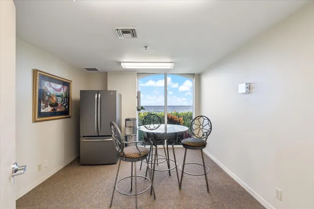 a view of a chairs and table under an umbrella with a garden