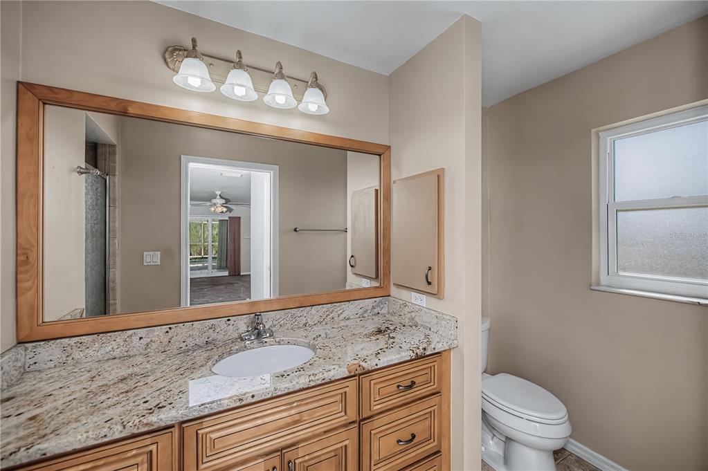 443 Fairmont Terrace Port Charlotte, FL 33954 - Photo 43 of 77 a bathroom with a granite countertop sink a toilet and a mirror