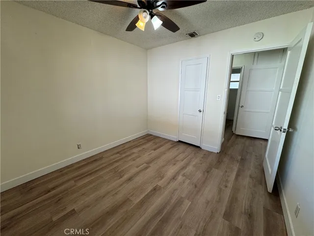 an empty room with wooden floor and ceiling fan