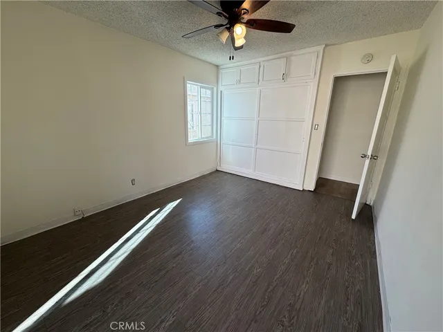 an empty room with wooden floor fan and windows
