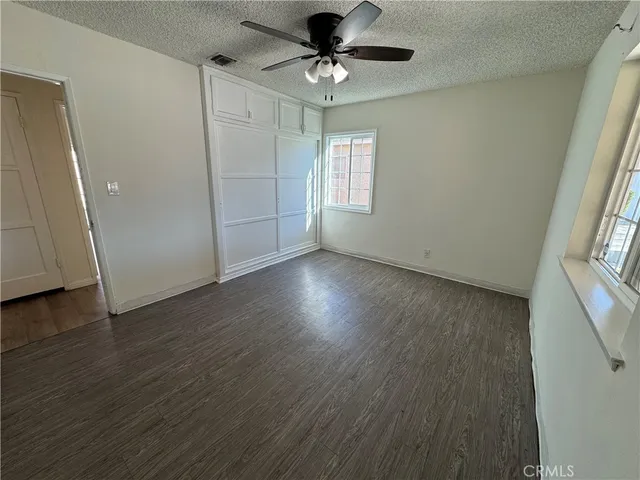 an empty room with wooden floor chandelier fan and windows