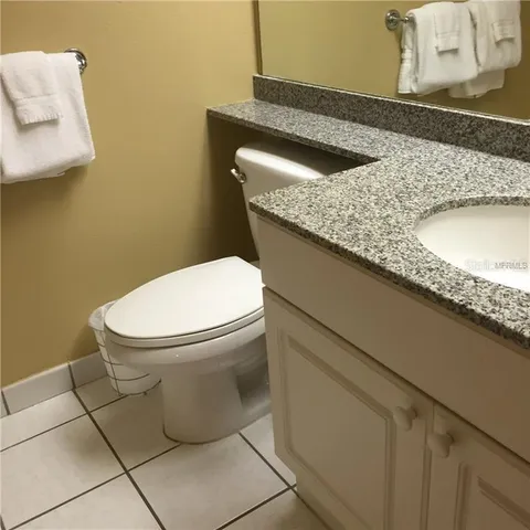 a bathroom with a granite countertop sink and a toilet