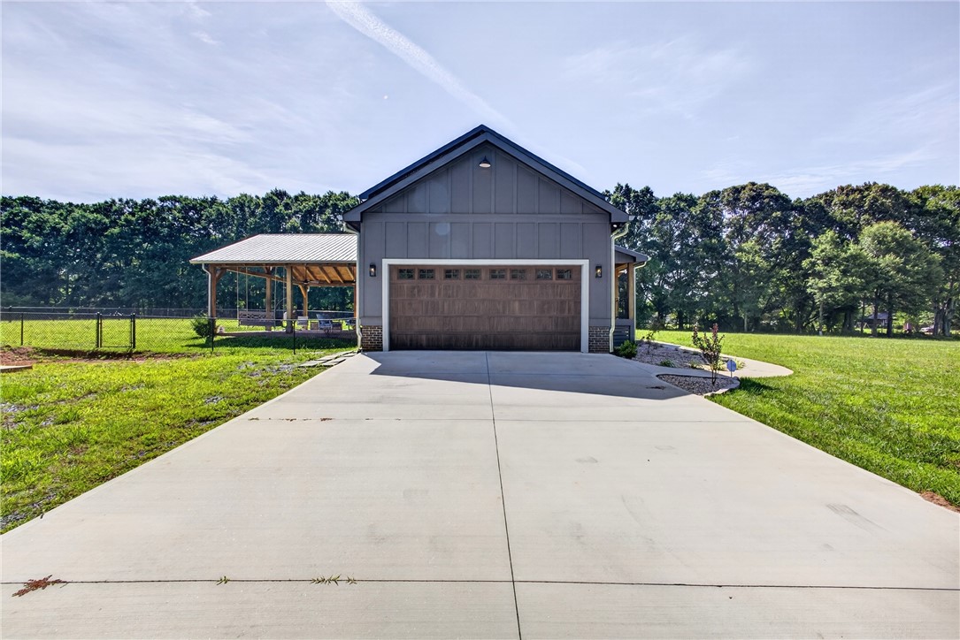 5016 Copeland Road Belton, SC 29627 - Photo 38 of 45 A spacious driveway leads to a charming detached garage with an adjacent covered patio area, perfect for outdoor enjoyment.