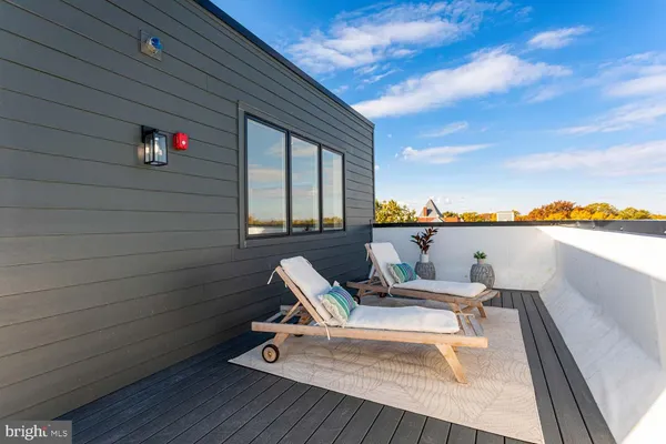 a roof deck with a table and chairs with wooden floor and fence