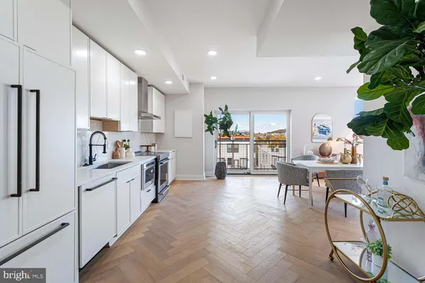 a kitchen with stainless steel appliances granite countertop a table chairs and a refrigerator