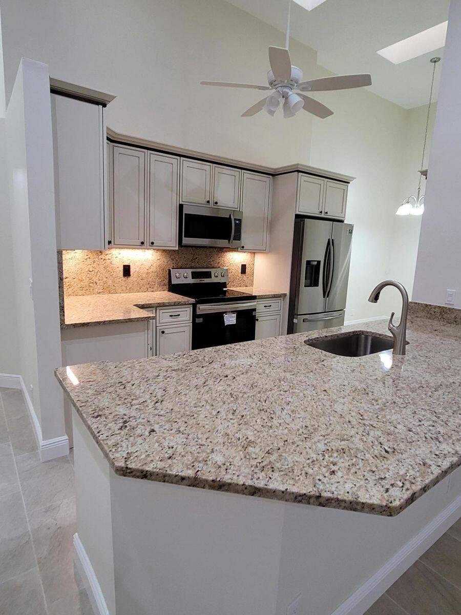 11000 Ladera Lane, Unit B Boca Raton, FL 33498 - Photo 12 of 29 a kitchen with stainless steel appliances granite countertop a sink stove and refrigerator