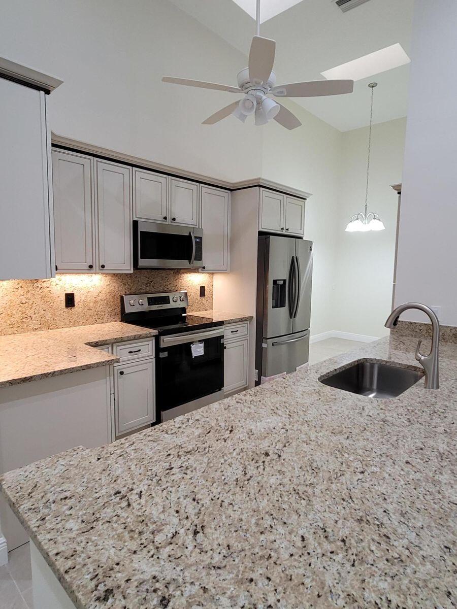 11000 Ladera Lane, Unit B Boca Raton, FL 33498 - Photo 9 of 29 a kitchen with stainless steel appliances granite countertop a sink stove and refrigerator