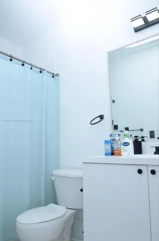 a bathroom with a sink a toilet and shower curtain
