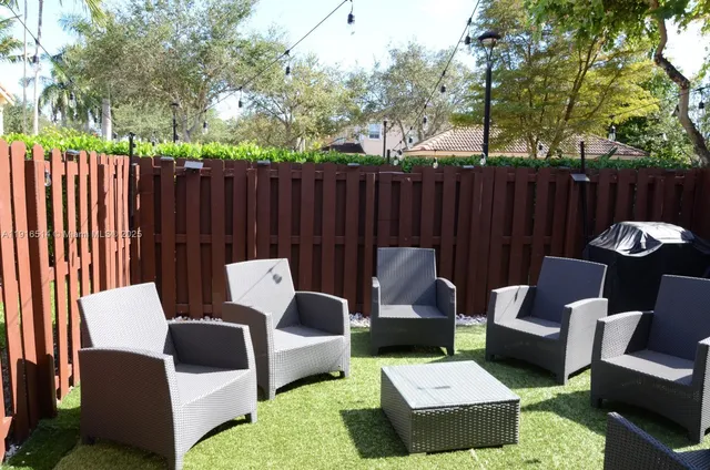a view of a patio with couches chairs and a wooden fence