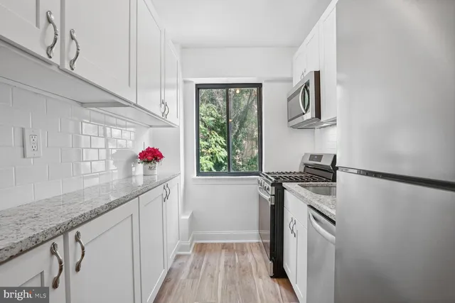a kitchen with granite countertop a white stove top oven and cabinetry
