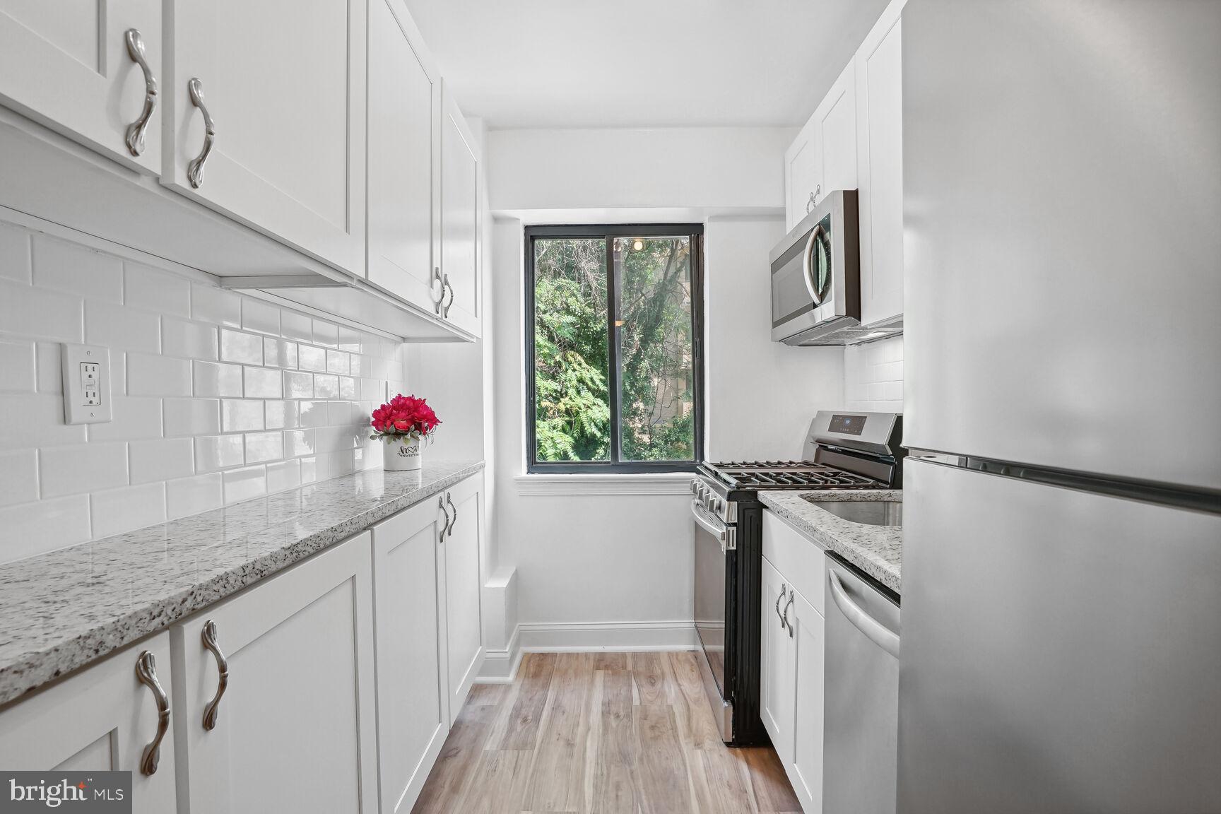 3901 Tunlaw Road Northwest, Unit 502 Washington, DC 20007 - Photo 6 of 34 a kitchen with granite countertop a white stove top oven and cabinetry