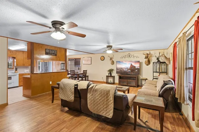 a living room with furniture a ceiling fan and a large window