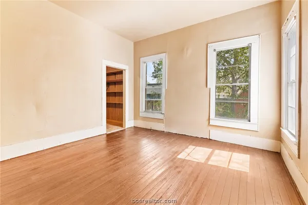a view of an empty room with wooden floor and a window