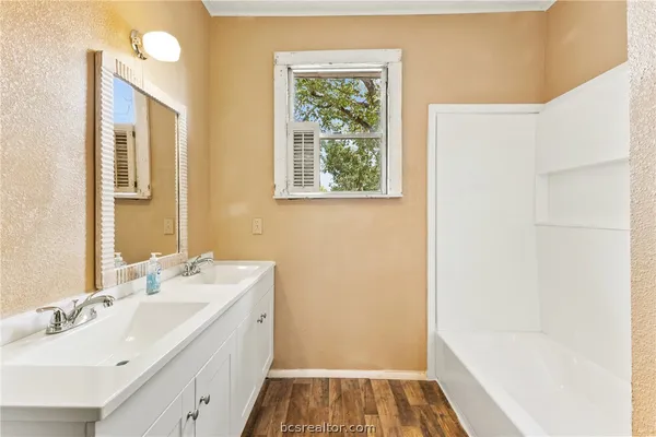 a bathroom with a tub sink and mirror