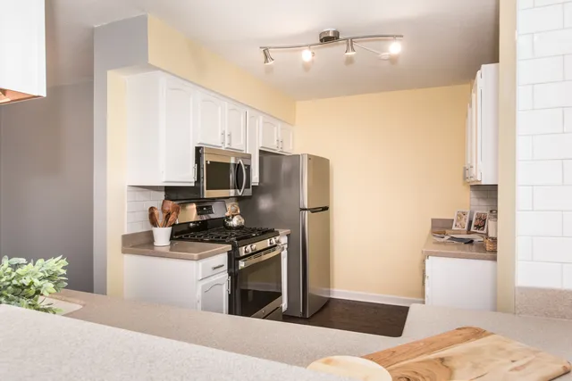 a kitchen with stainless steel appliances kitchen island granite countertop a refrigerator stove and sink