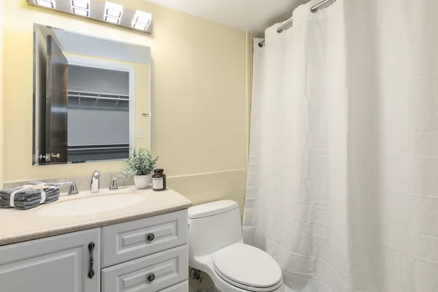 a bathroom with a granite countertop sink toilet and mirror