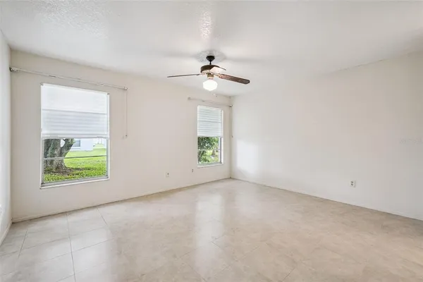 an empty room with windows and fan