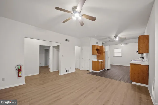 an empty room with wooden floor and ceiling fan