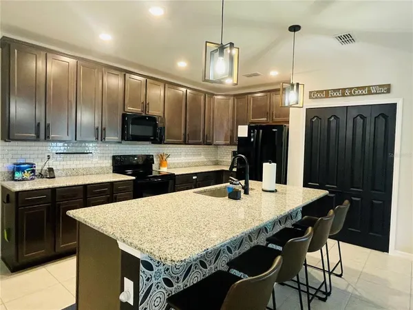 a kitchen with stainless steel appliances granite countertop a kitchen island a stove a table and chairs
