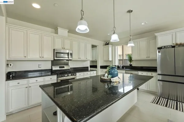 a kitchen with stainless steel appliances granite countertop a sink a stove and white cabinets