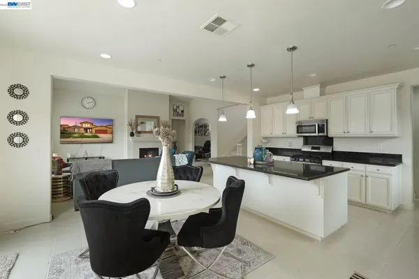 a kitchen with stainless steel appliances granite countertop a table chairs and a refrigerator