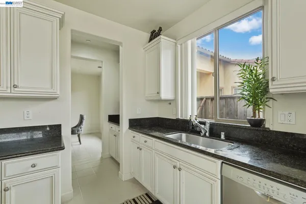 a kitchen with granite countertop a sink a stove and cabinets