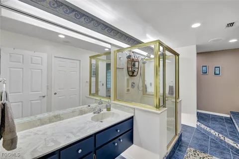 a bathroom with a granite countertop sink a mirror and a shower