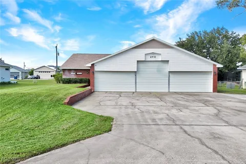 a view of a white house next to a yard and large trees