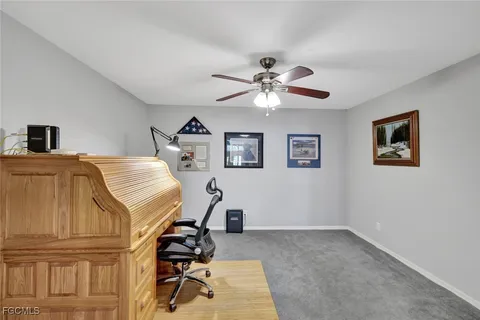 a view of a workspace with furniture and a ceiling fan