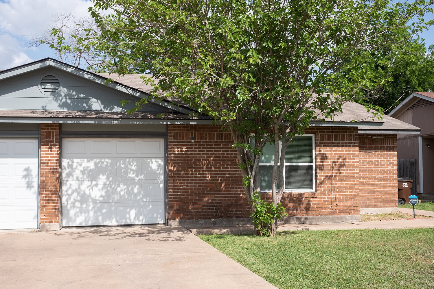 1107 Ridgemont Street Round Rock, TX 78664 - Photo 1 of 1 Ranch-style home with driveway, a front lawn, brick siding, and a garage