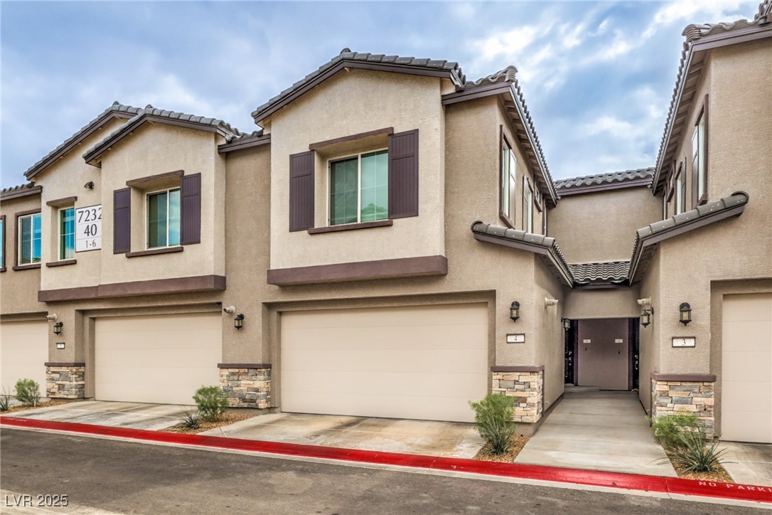 7232 North Decatur Boulevard, Unit 4 North Las Vegas, NV 89084 - Photo 2 of 36 Townhome / multi-family property featuring stone siding, concrete driveway, an attached garage, and stucco siding